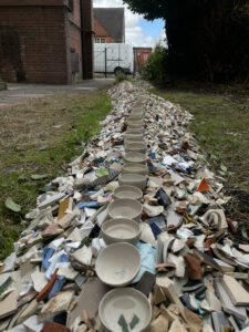 a pile of ceramic shards with small pinched pots on top